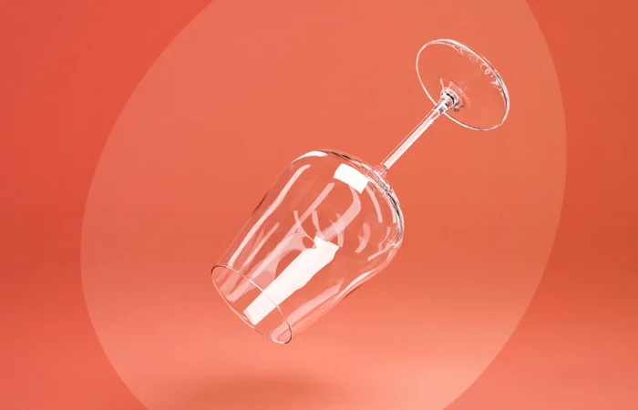 An empty wine glass floating against a coral background, symbolizing the clarity and lightness of an alcohol-free lifestyle.