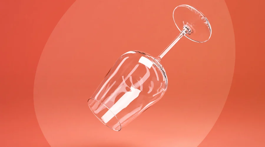 An empty wine glass floating against a coral background, symbolizing the clarity and lightness of an alcohol-free lifestyle.