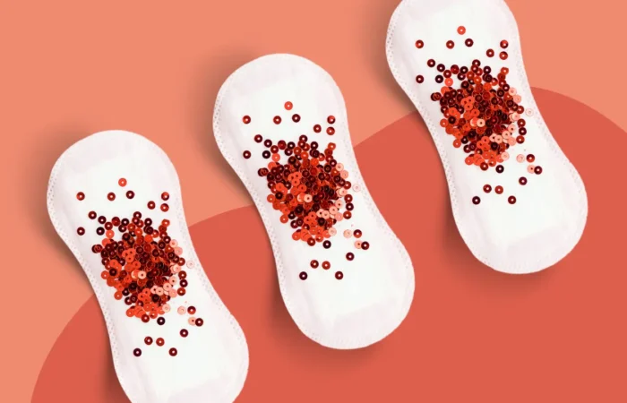 Trois serviettes hygiéniques sur fond corail avec des paillettes rouges symbolisant des règles abondantes et des saignements utérins anormaux en périménopause.