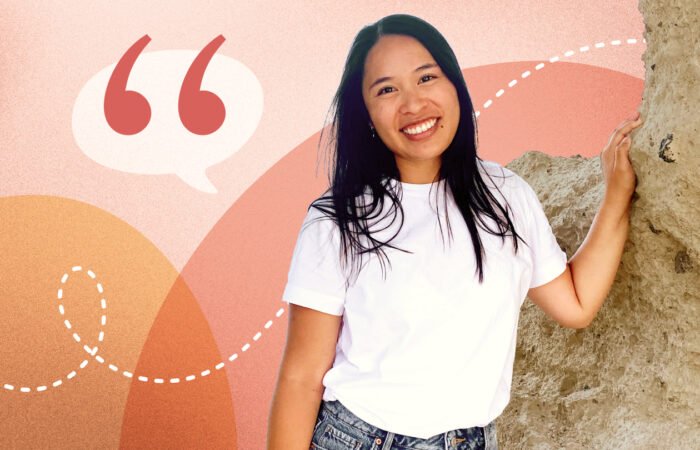 A smiling woman leaning against a stone wall, overlaid on an abstract coral and peach background with a large quotation mark icon for a Coral member testimonial.
